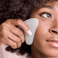 Person using a skincare jade gua sha tool on their face
