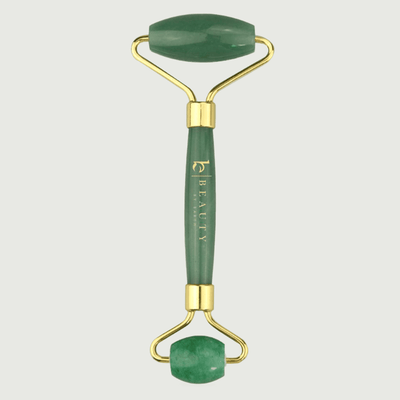 Green jade roller with gold accents on a light gray background