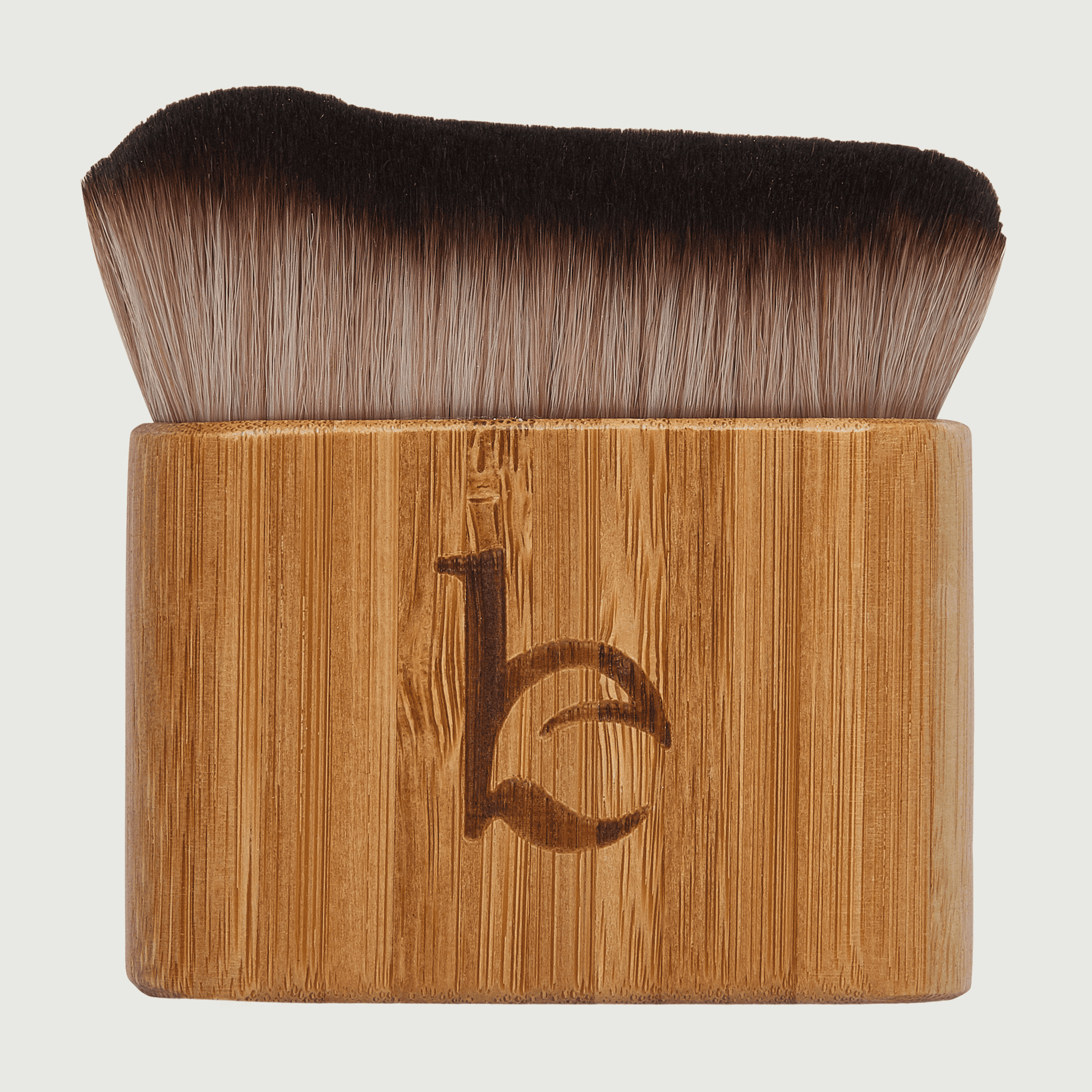 Makeup brush with wooden handle and black bristles on a light gray background