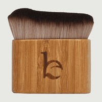 Makeup brush with wooden handle and black bristles on a light gray background