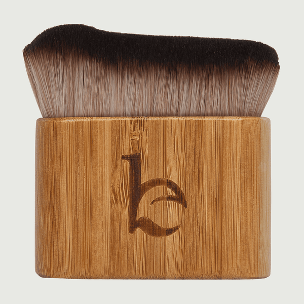 Makeup brush with wooden handle and black bristles on a light gray background