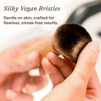 Makeup brush with silky vegan bristles held by a hand, with text about the bristle quality.