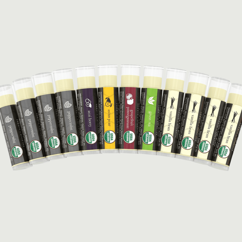 Row of lip balm tubes with various flavors on a light gray background