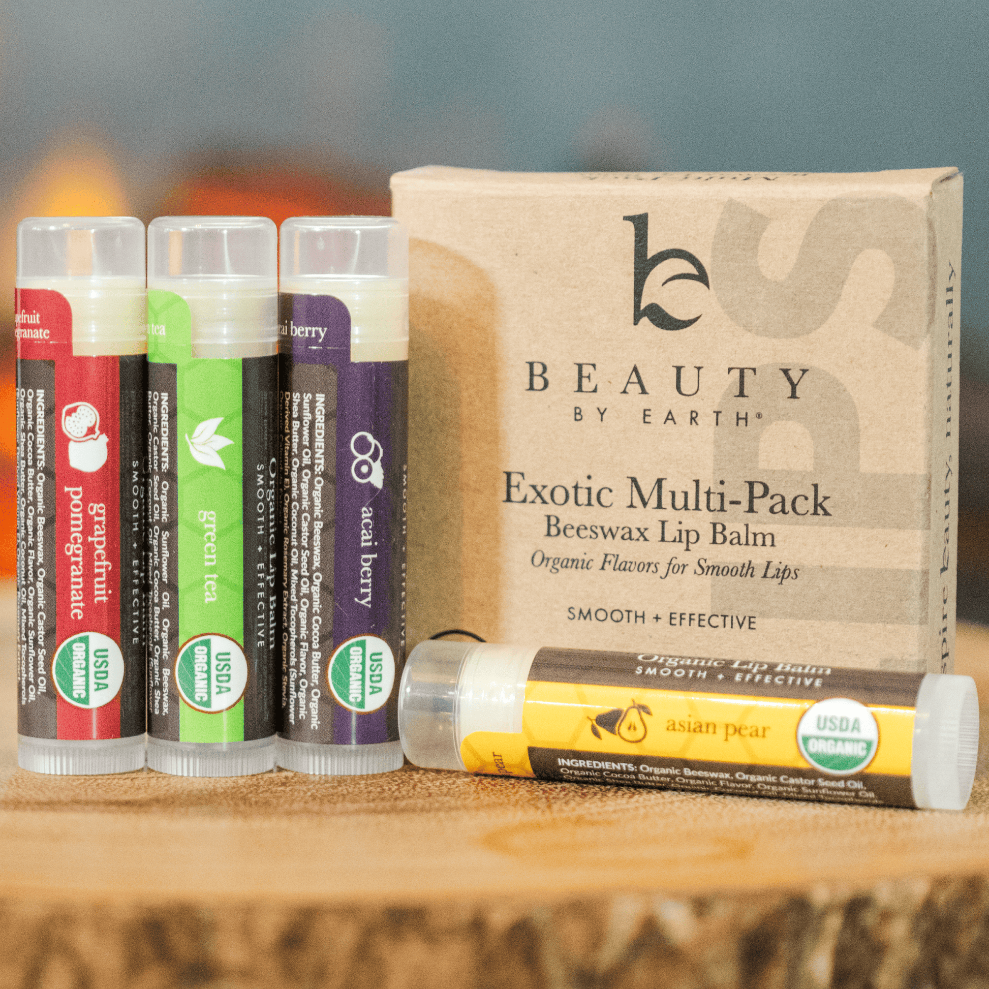 Collection of Beauty by Earth lip balm sticks on a wooden surface with a branded box in the background.