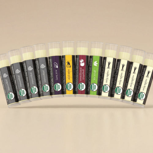 Row of lip balm tubes with various flavors on a light gray background