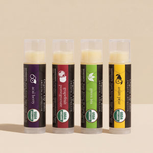 Four organic lip balm tubes with different flavors on a beige background