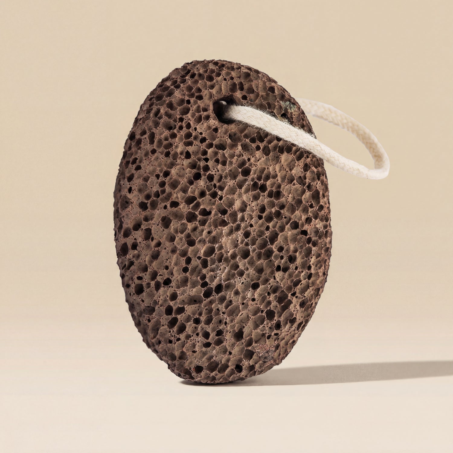 Brown pumice stone with a white string on a beige background