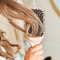 Person holding a hairbrush with bristles against their hair, blurred background