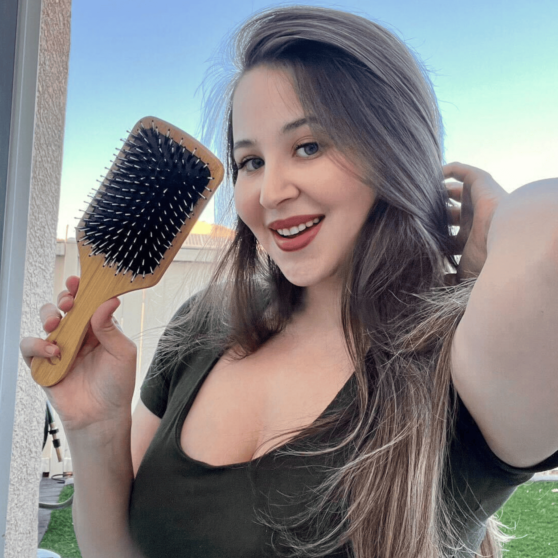 Woman holding a hairbrush and smiling outdoors