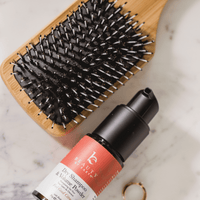 Hairbrush and bottle of dry shampoo on a marble surface