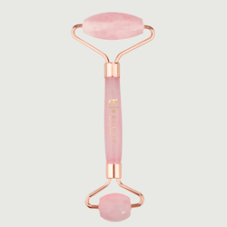 Pink and rose gold facial roller on a light gray background