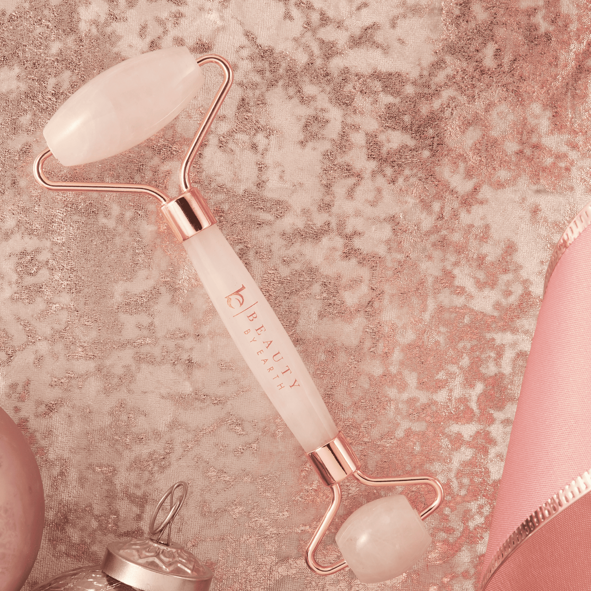 Beauty roller with rose gold and white design on a textured pink background