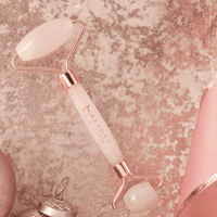 Beauty roller with rose gold and white design on a textured pink background