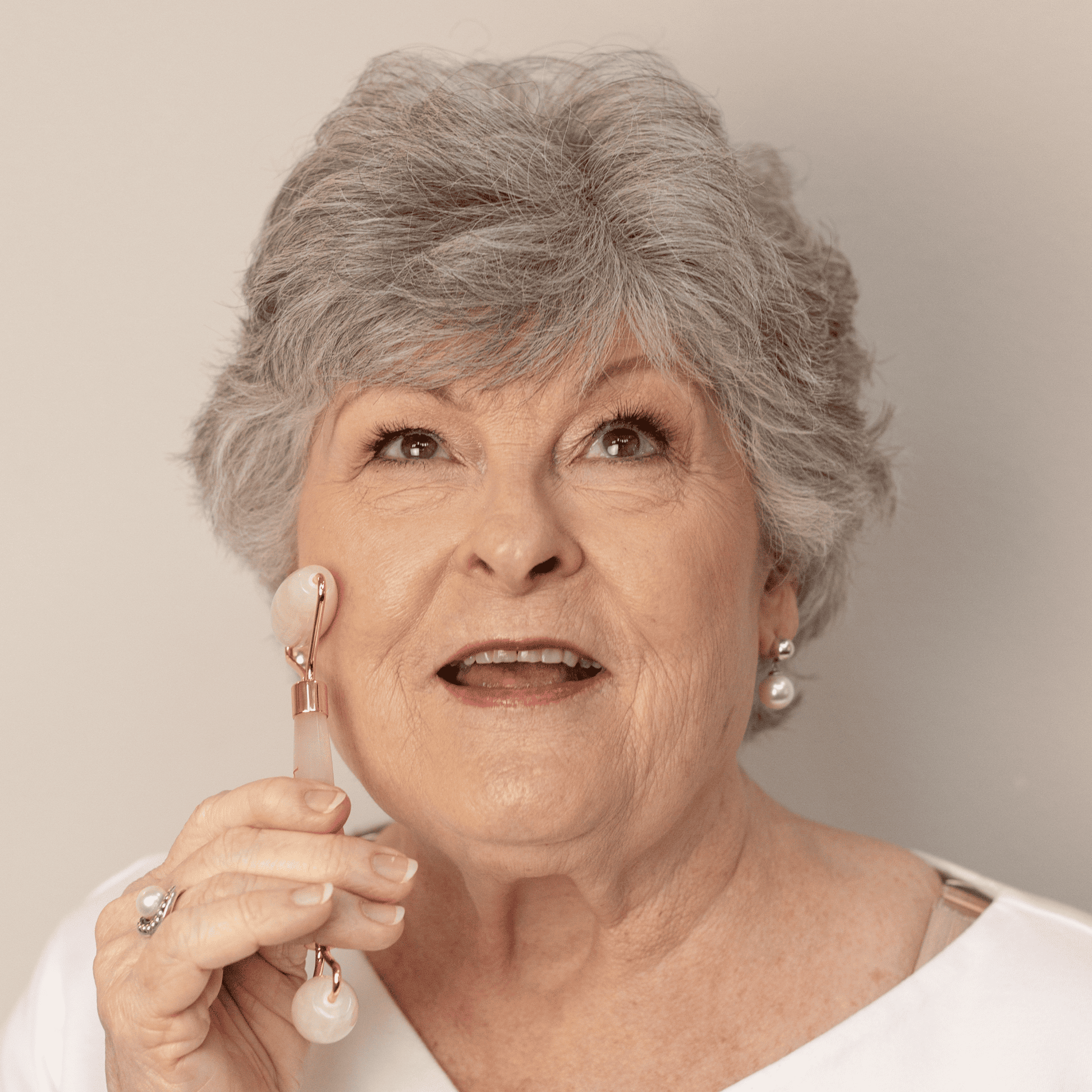 Woman holding a white earbud against a neutral background