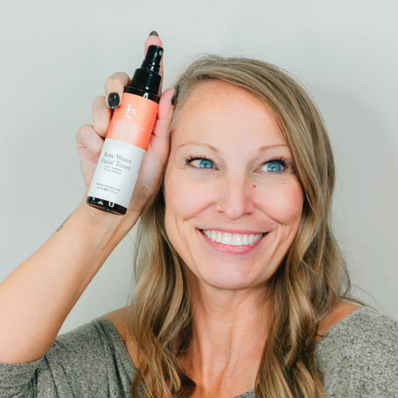 Woman holding a bottle of facial toner with a plain background