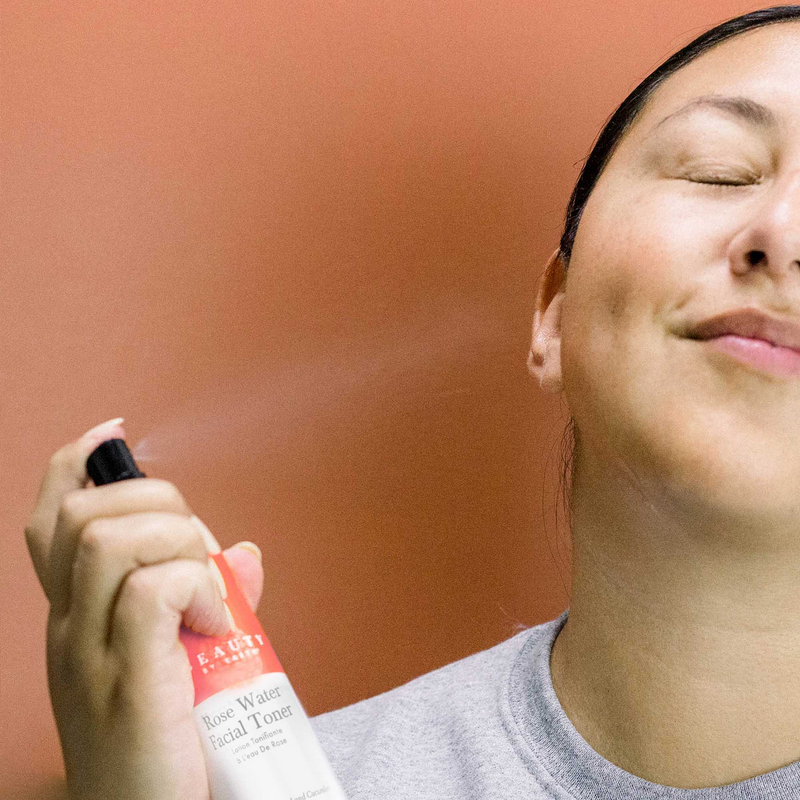 Person using a facial toner spray with a blurred background