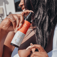 Person applying a hair care product to another person's hair outdoors