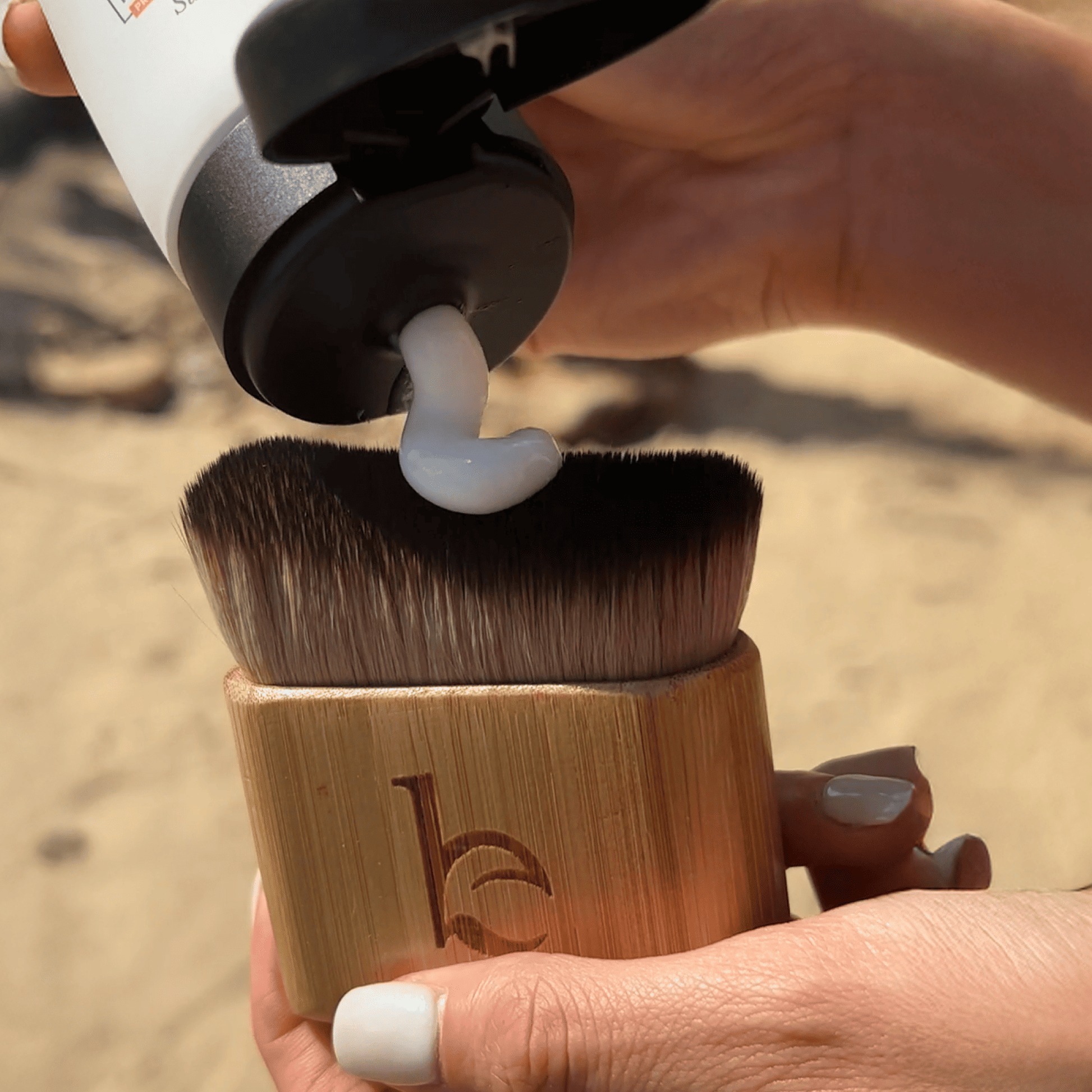 Texture white lotion of Beauty by Earth self tanning lotion body coming down on a kabuki body blending brush