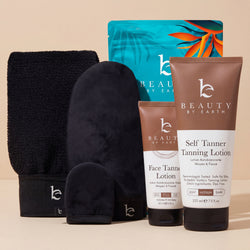 Beauty by Earth self tanner tanning lotion and face lotion tubes, next to the self tanning applicator kit with body, face and exfoliating mitt