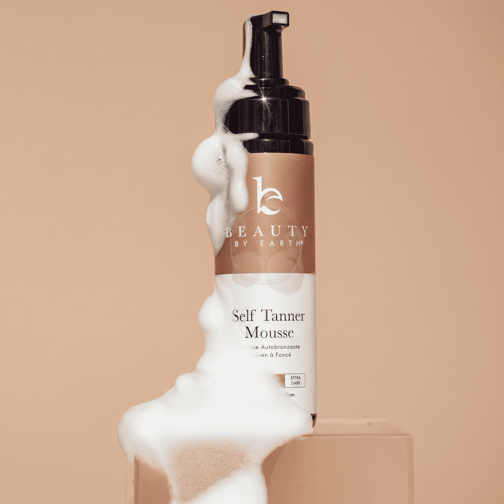 Beauty by Earth Self Tanner Mousse bottle with foam on a beige background