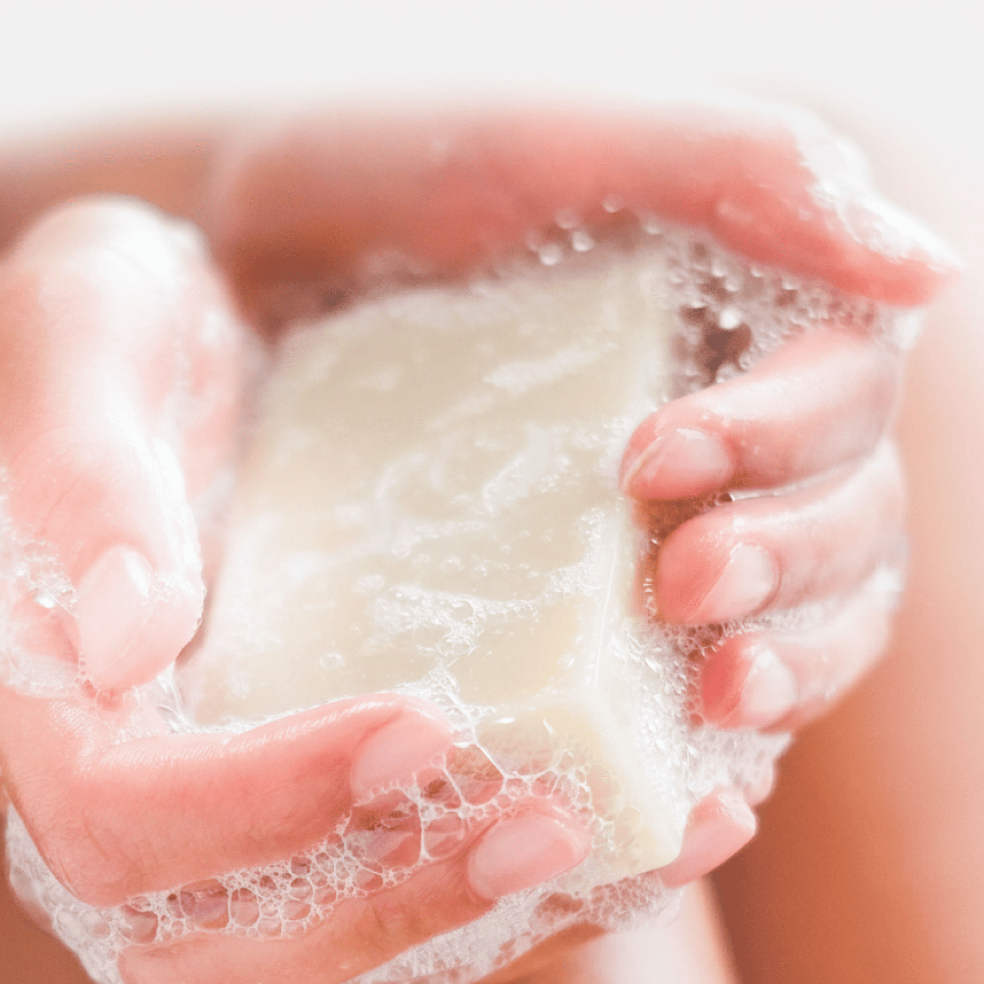 Close-up of hands holding a bar of soap with bubbles