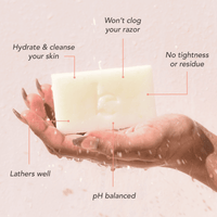 Hand holding a bar of soap with text highlighting its benefits on a light pink background
