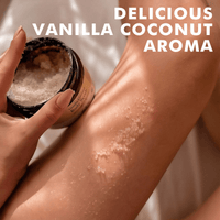 Person applying a scrub from a jar to their leg with text 'Delicious Vanilla Coconut Aroma'.