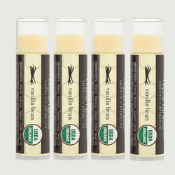 Four Vanilla Bean Organic lip balms on a light gray background
