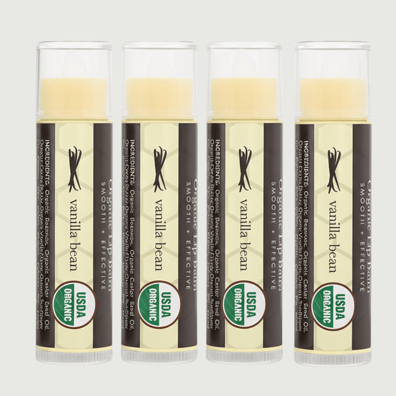 Four Vanilla Bean Organic lip balms on a light gray background