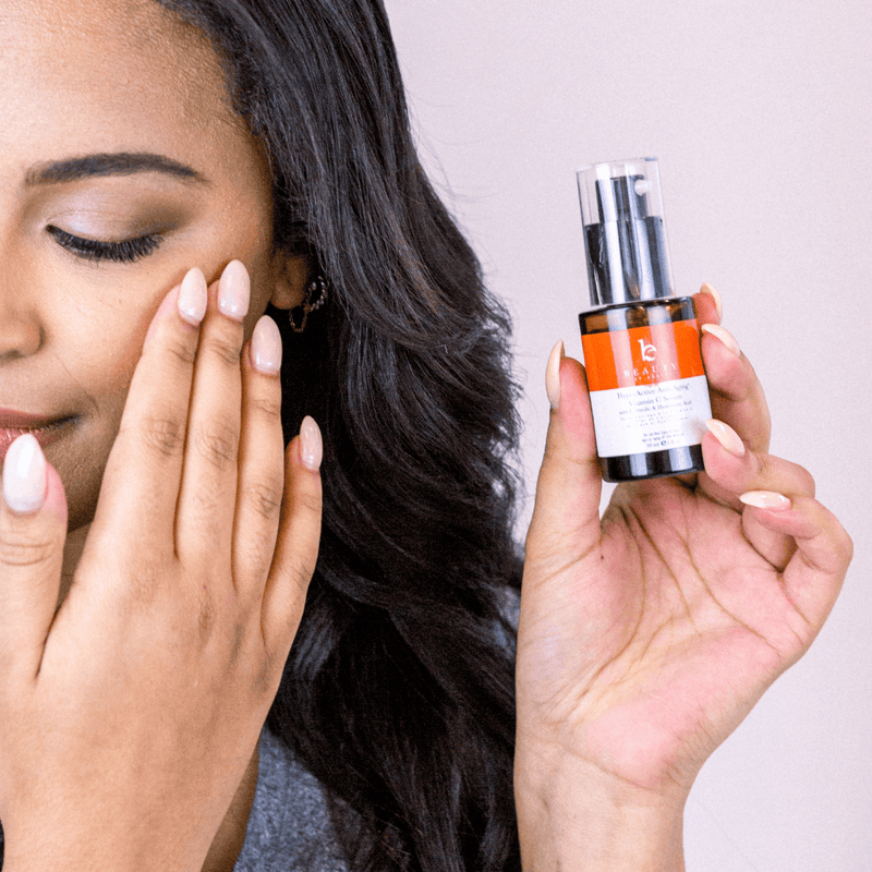 Woman holding a skincare serum bottle with a neutral background