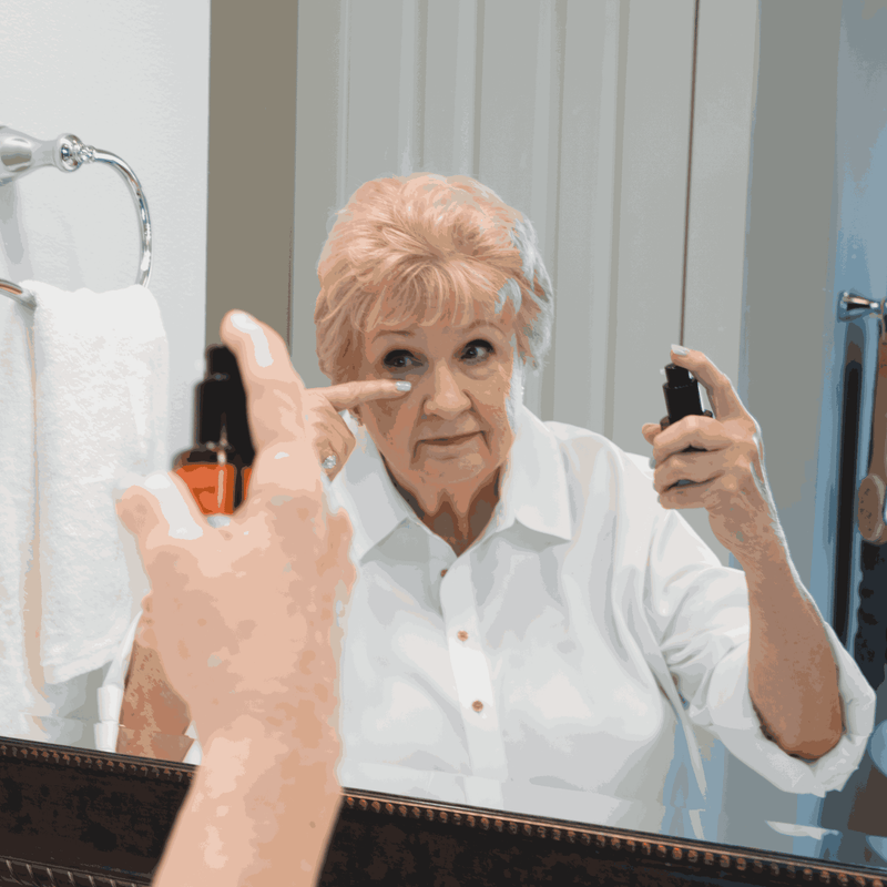Woman applying makeup in front of a mirror