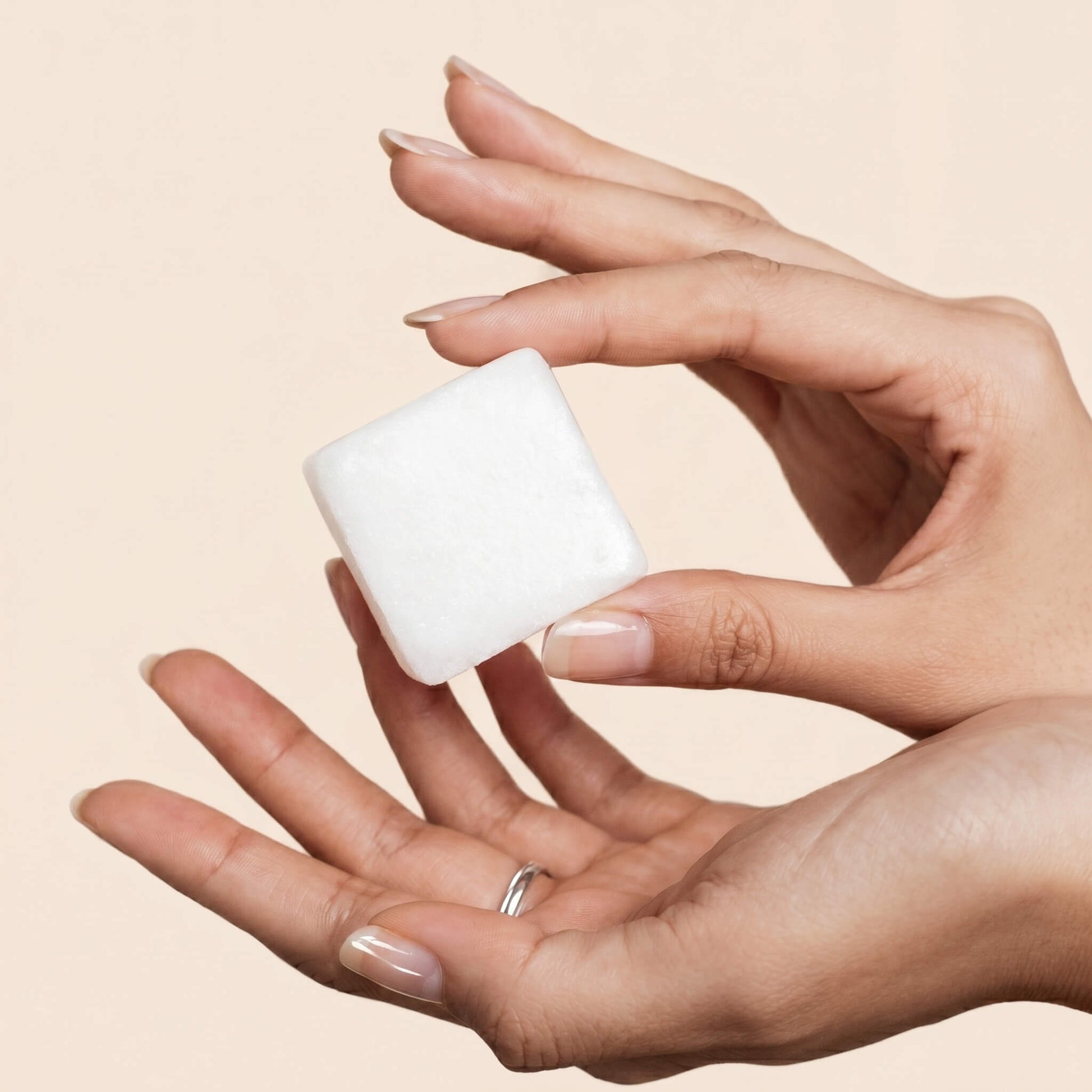 A hand Holding a Beauty by Earth shower steamer cube - Natural and organic ingredients, vegan, made in the USA
