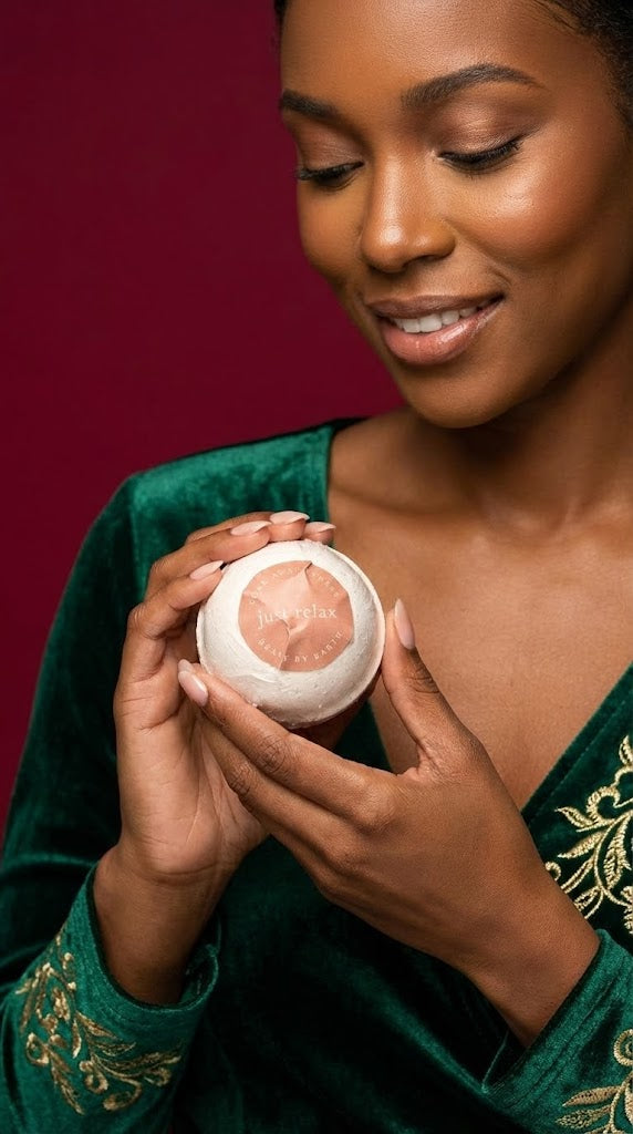 Woman holding a round beauty by earth bath bomb product against a red background