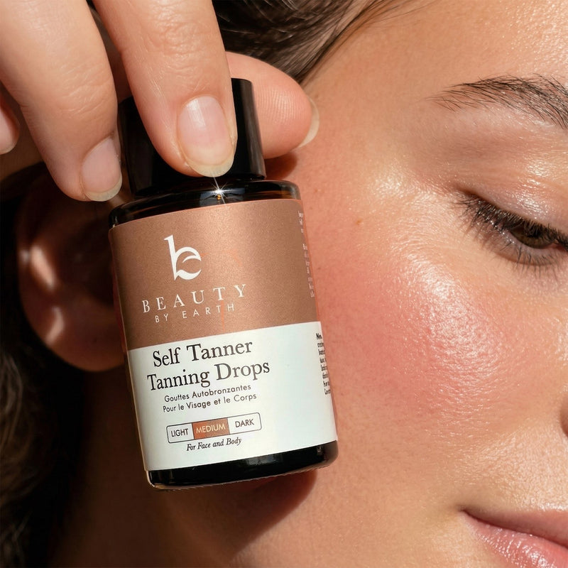 Bottle of Beauty by Earth Self Tanner Tanning Drops held near a person's face.