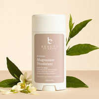 Beauty by Earth magnesium deodorant with green leaves and flowers on a beige background